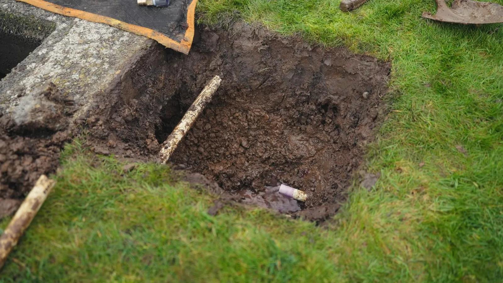A technician cutting into a water line to reach a leak, representing Water Line Repair & Replacement service
